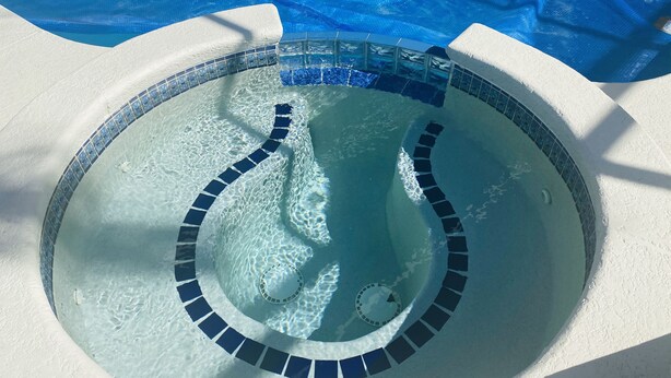 Una piscina circular con borde de mosaicos azules y desagüe central.