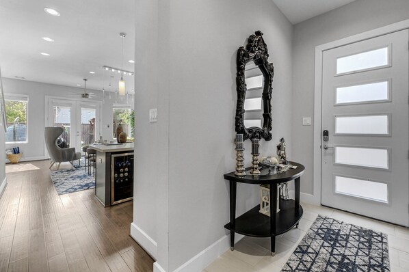 A modern entryway with a black console table, a large mirror, and a patterned rug.