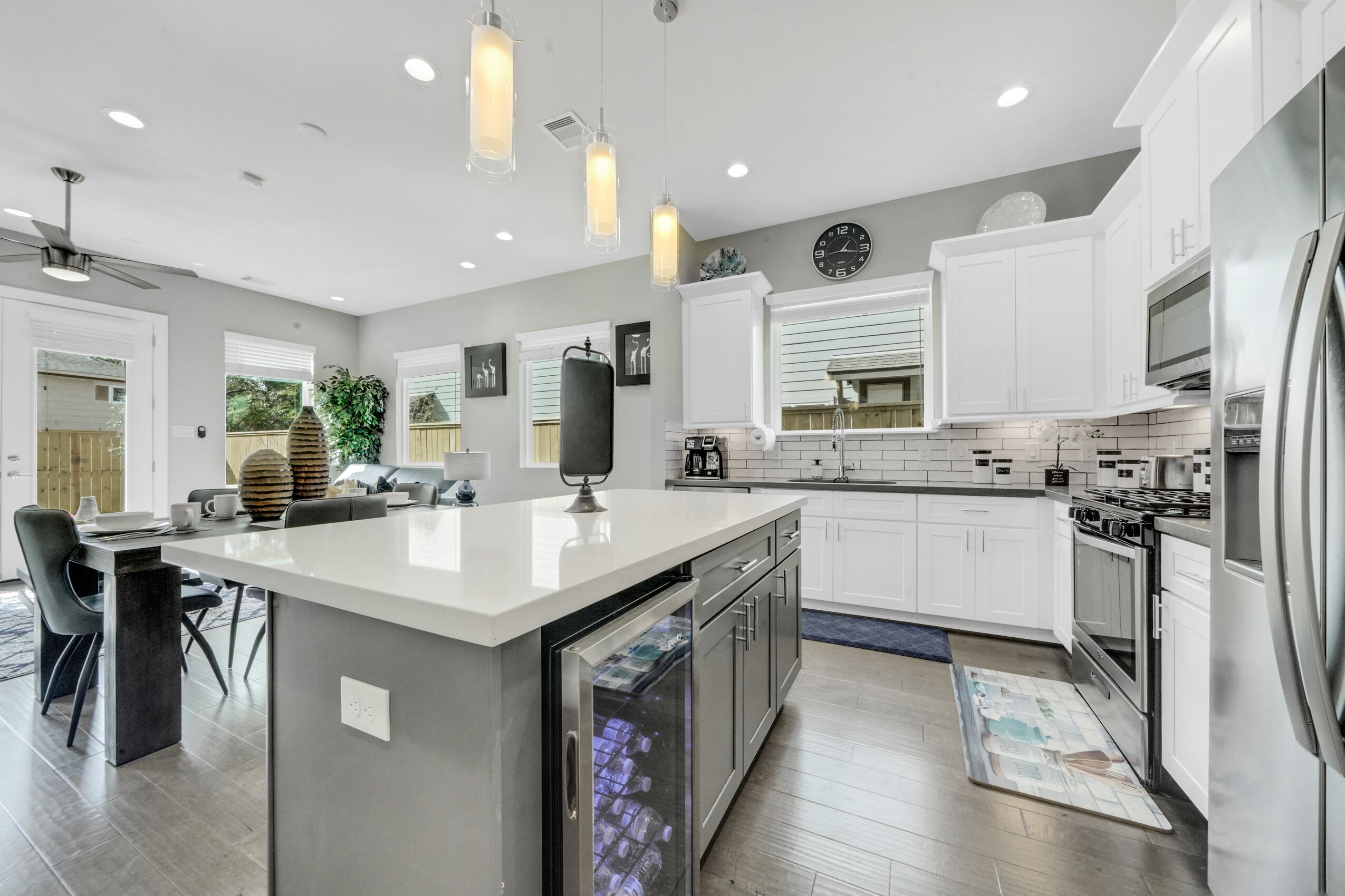 A modern kitchen with white cabinetry, stainless steel appliances, and pendant lighting.