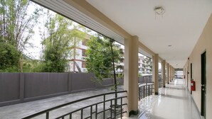 A corridor with a metal railing, a fire extinguisher, and a view of greenery outside. - OYO 75390 Sunee Place Hotel (Ban Chang)