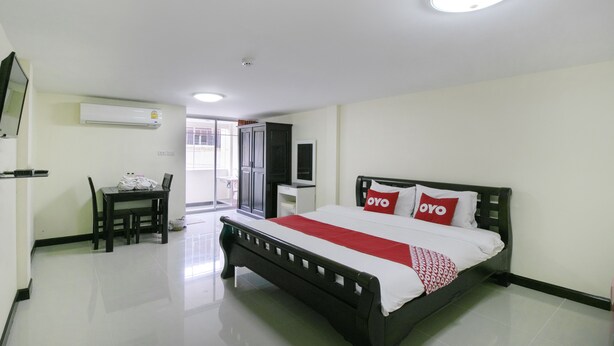 A hotel room with a bed, a desk, a chair, an air conditioning unit, and a television. - OYO 75390 Sunee Place Hotel (Ban Chang)