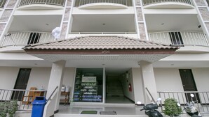 A multi-story building with balconies, a covered entrance, and a visible staircase leading to the upper floors. - OYO 75390 Sunee Place Hotel (Ban Chang)