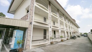 A multi-story hotel with balconies, a parking area, and potted plants. - OYO 75390 Sunee Place Hotel (Ban Chang)