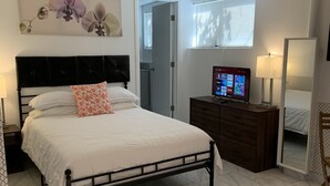 A neatly arranged bedroom with a bed, a dresser, a television, and a window with blinds. - Shabby Chic Studio in LA Hills (Alhambra)