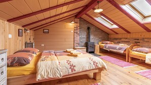 A cozy attic bedroom with wooden beams, a brick fireplace, and skylights. - Pivka Lovely Duplex With Sauna, Pivka, Slovenia (Pivka)