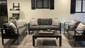 A modern living room with a gray sofa, two armchairs, a coffee table, and a ceiling fan.