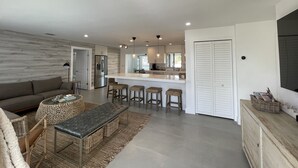 A modern kitchen with a central island, bar stools, and a built-in refrigerator.