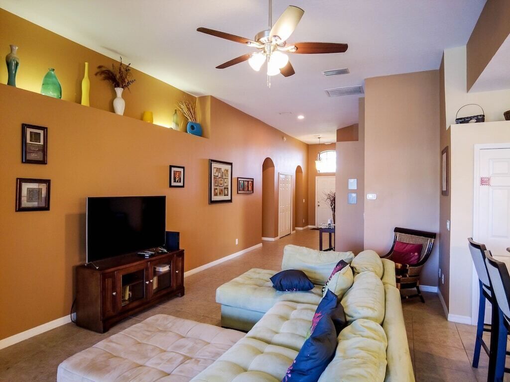 A living room with a sofa, TV, and ceiling fan.