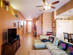 Relax in this inviting living room with a comfortable sofa, flat-screen TV, and ceiling fan.