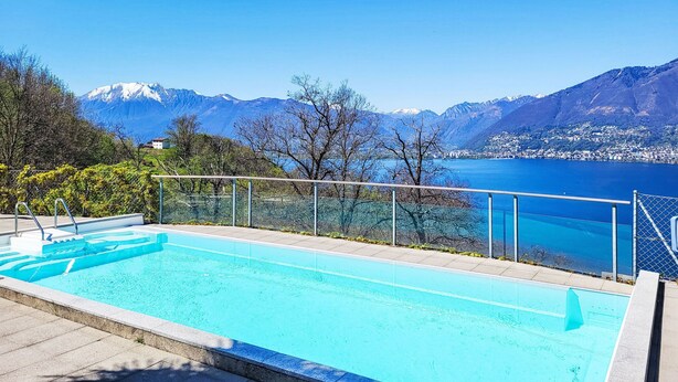 Una piscina con vistas despejadas a un lago y montañas al fondo.