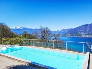 Ein Schwimmbad mit Blick auf einen See und Berge im Hintergrund.
