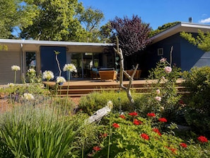 Il s’agit d’une propriété résidentielle dotée d’un patio couvert, d’un espace salon extérieur et d’un jardin agrémenté de diverses plantes et fleurs.