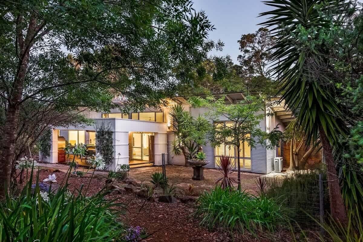 Una casa moderna con un jardín cuidado, una entrada visible y un ventanal grande.