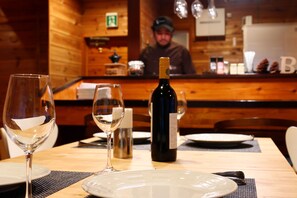 Un intérieur en bois avec une table dressée pour le dîner, une bouteille de vin et une bougie.