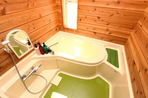 Une salle de bain rustique, avec des murs en bois, comprenant une baignoire, un miroir et des articles de toilette.