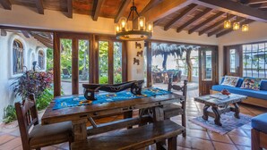A spacious room with a wooden dining table, benches, a blue sofa, and a chandelier.