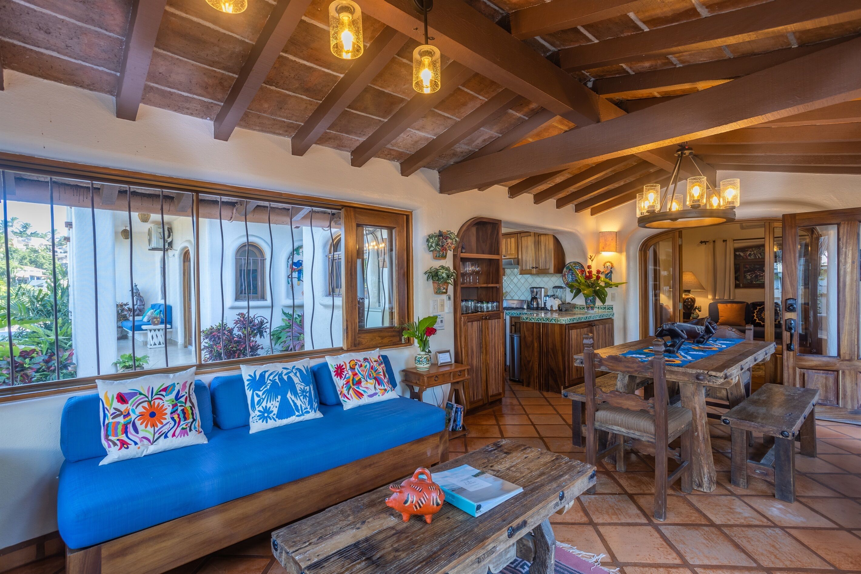 Un interior acogedor y rústico con un sofá azul, mesa de comedor de madera y vigas de madera a la vista.