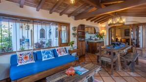 A cozy, rustic interior with a blue sofa, wooden dining table, and exposed wooden beams.