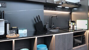 A modern kitchen with a black countertop, stainless steel appliances, and a built-in oven. - ST Signature Bugis Beach, DAYUSE, 8-9 hours: check in 8AM or 11AM (Singapore)
