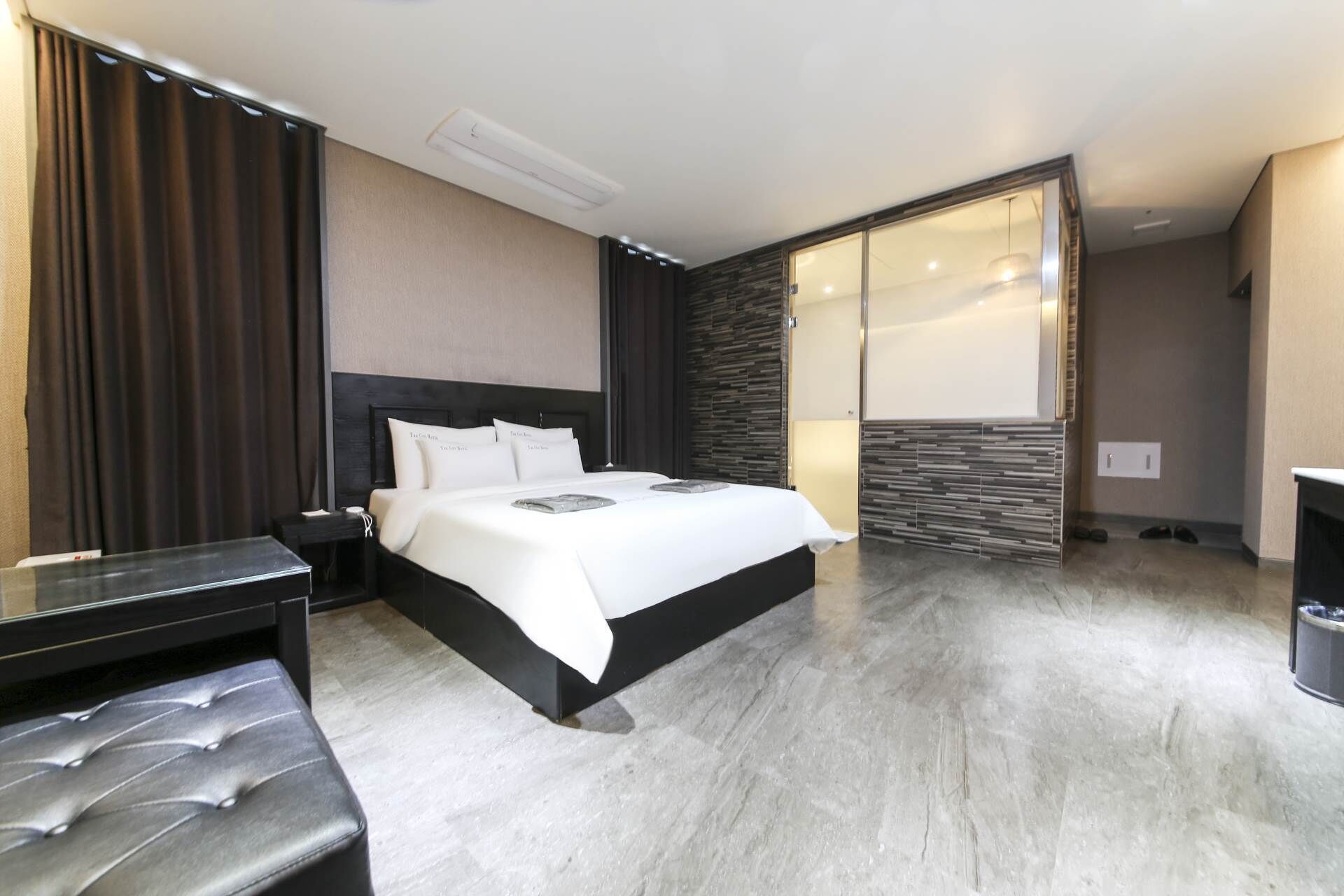 Une chambre d’hôtel moderne avec un grand lit, une table de chevet, un banc et une armoire.