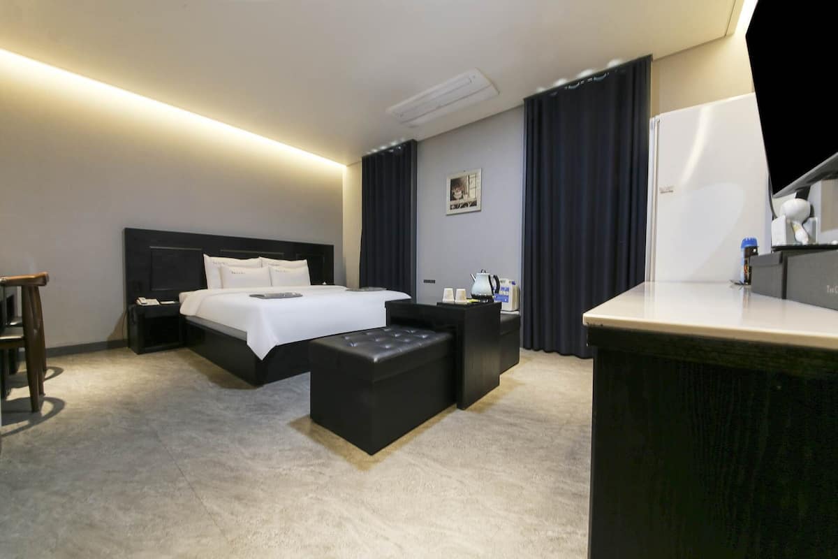 Una habitación de hotel moderna con una cama grande, un escritorio y una silla.
