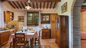 Una cocina rústica con armarios de madera, una mesa de comedor para cuatro personas y un ventanal con vistas a la vegetación.