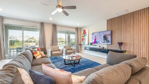 Ein modernes Wohnzimmer mit einem großen Sofa, einem Couchtisch und einem an der Wand befestigten Flachbildfernseher.