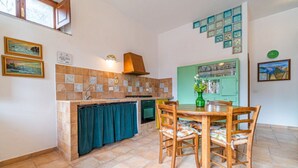 A compact kitchen with a tiled backsplash, a built-in oven, and a dining area with wooden chairs.
