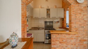 Une cuisine avec une arche en briques, des meubles blancs, une cuisinière et un four.