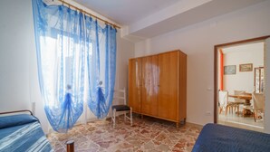 Une pièce comprenant un lit, une armoire en bois, une chaise et une table à manger avec des chaises.