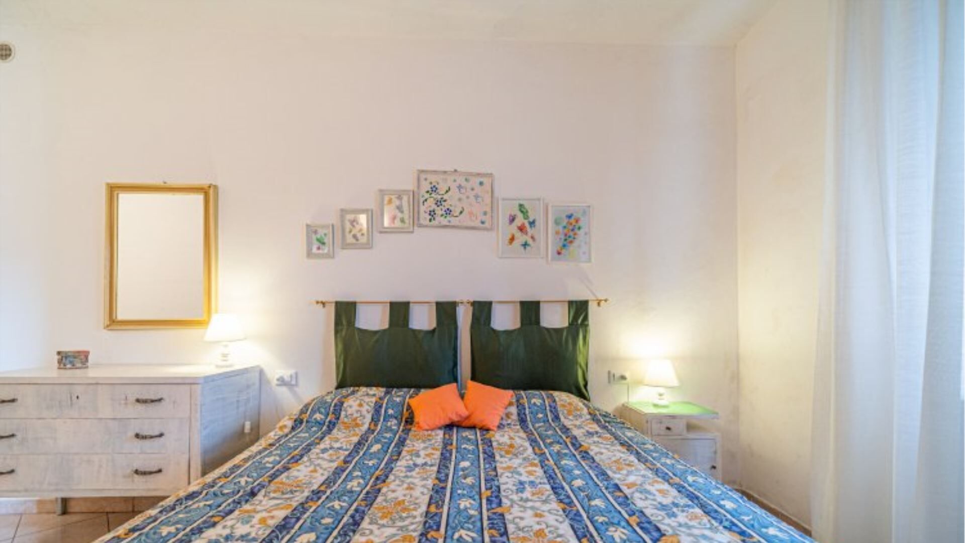 A bedroom with a bed, two bedside tables, a dresser, and a mirror.