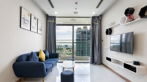 A modern living room with a sofa, ottoman, and a flat-screen TV mounted on the wall.