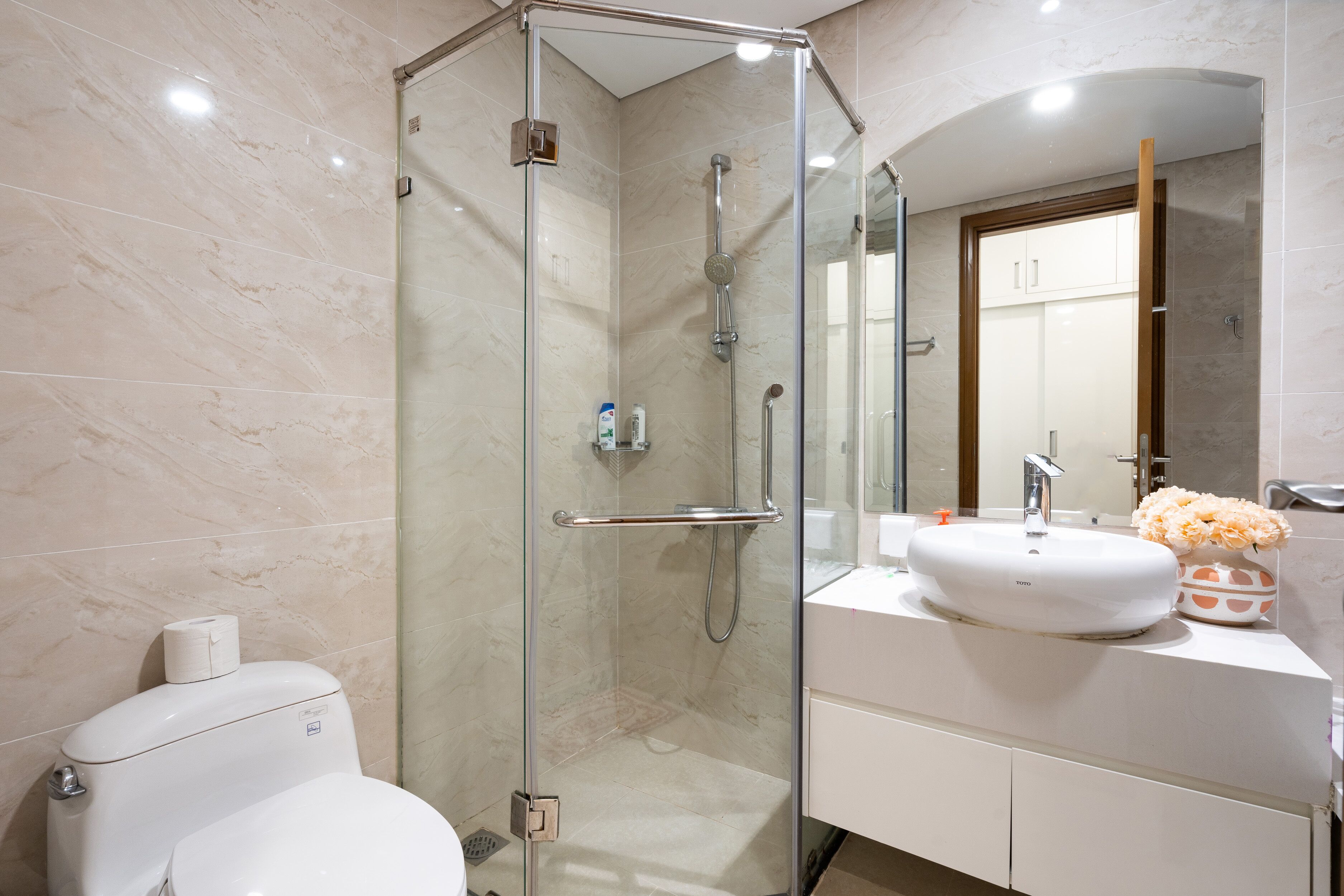A modern bathroom with a glass-enclosed shower, a white sink, and a toilet.