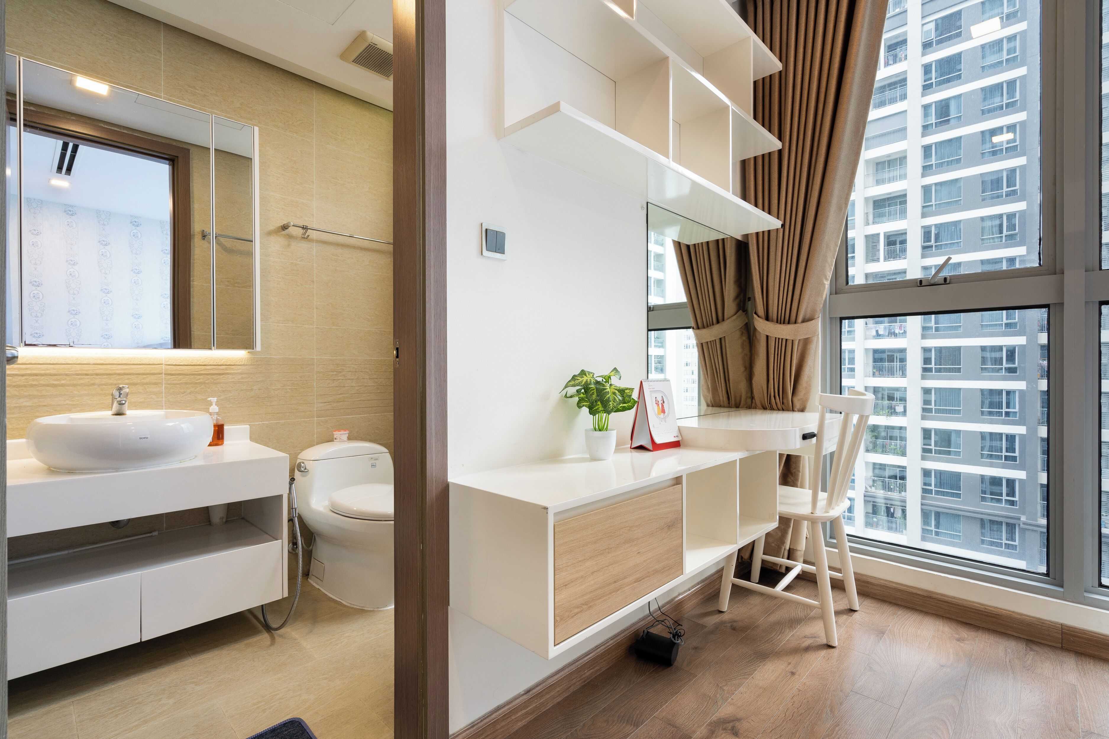 A modern bathroom with a large mirror, white vanity, and a window with a view of a building.