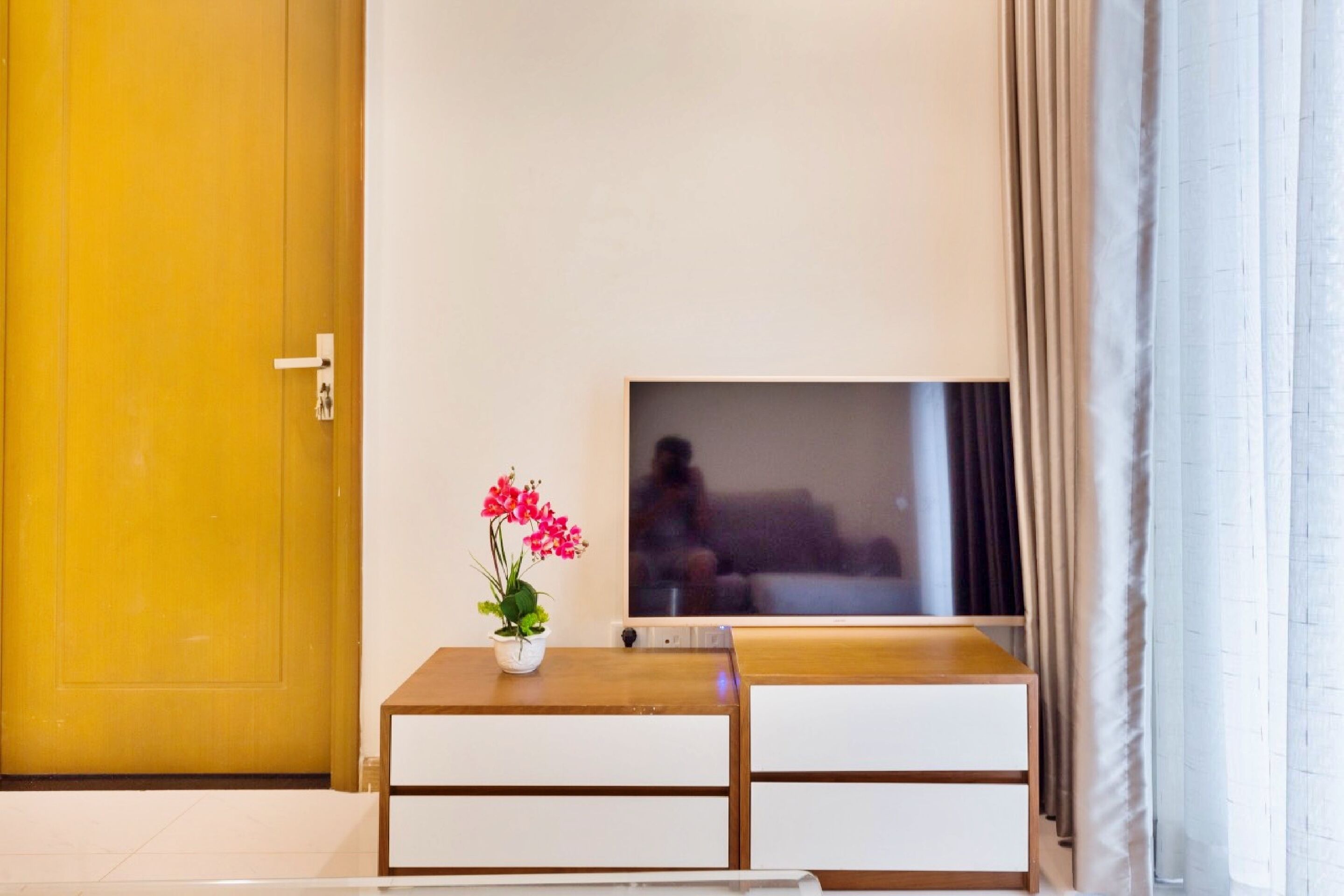 A room with a wooden desk, a TV on the wall, and a door.