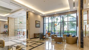 A spacious lobby with a marble floor, comfortable seating, large windows, and a view of the outdoors.