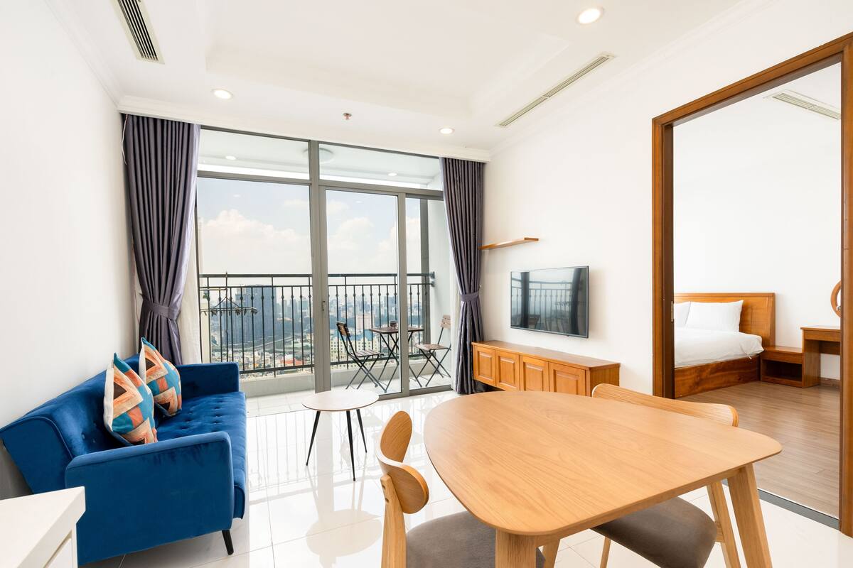 Et moderne hotelværelse med balkon, sofa, spisebord og fjernsyn.