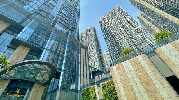 A modern high-rise building with a glass facade and a prominent logo on the lower level.