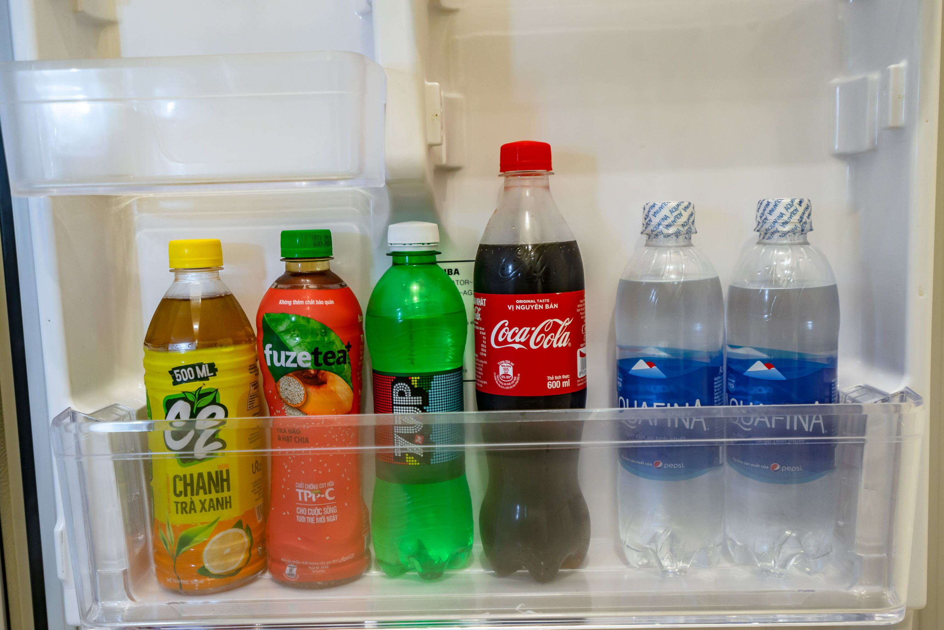A refrigerator with various beverages including Fuze Tea, Coca-Cola, and Pepsi.
