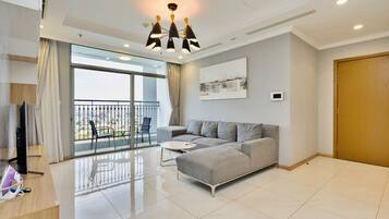 Een moderne woonkamer met een grijze bank, een ronde salontafel en een groot raam met balkon.