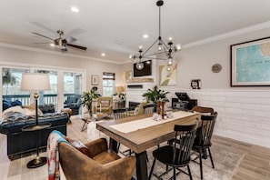 Un salon moderne avec un coin repas, comprenant une table à manger en bois, des canapés en cuir et un ventilateur de plafond.
