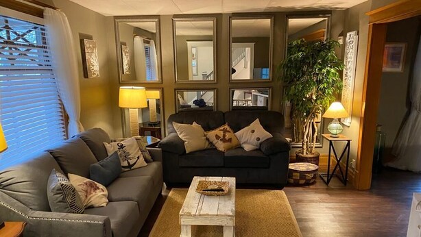 Un salon avec un canapé gris, une table basse blanche et un grand miroir.