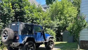 Un véhicule tout-terrain bleu est garé dans l’allée d’une maison.