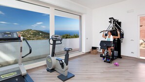 Amplia habitación con un gran ventanal que ofrece una vista panorámica, una caminadora y una máquina de pesas.