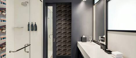 A modern bathroom with a shower, a vanity with a mirror, and a patterned wall.