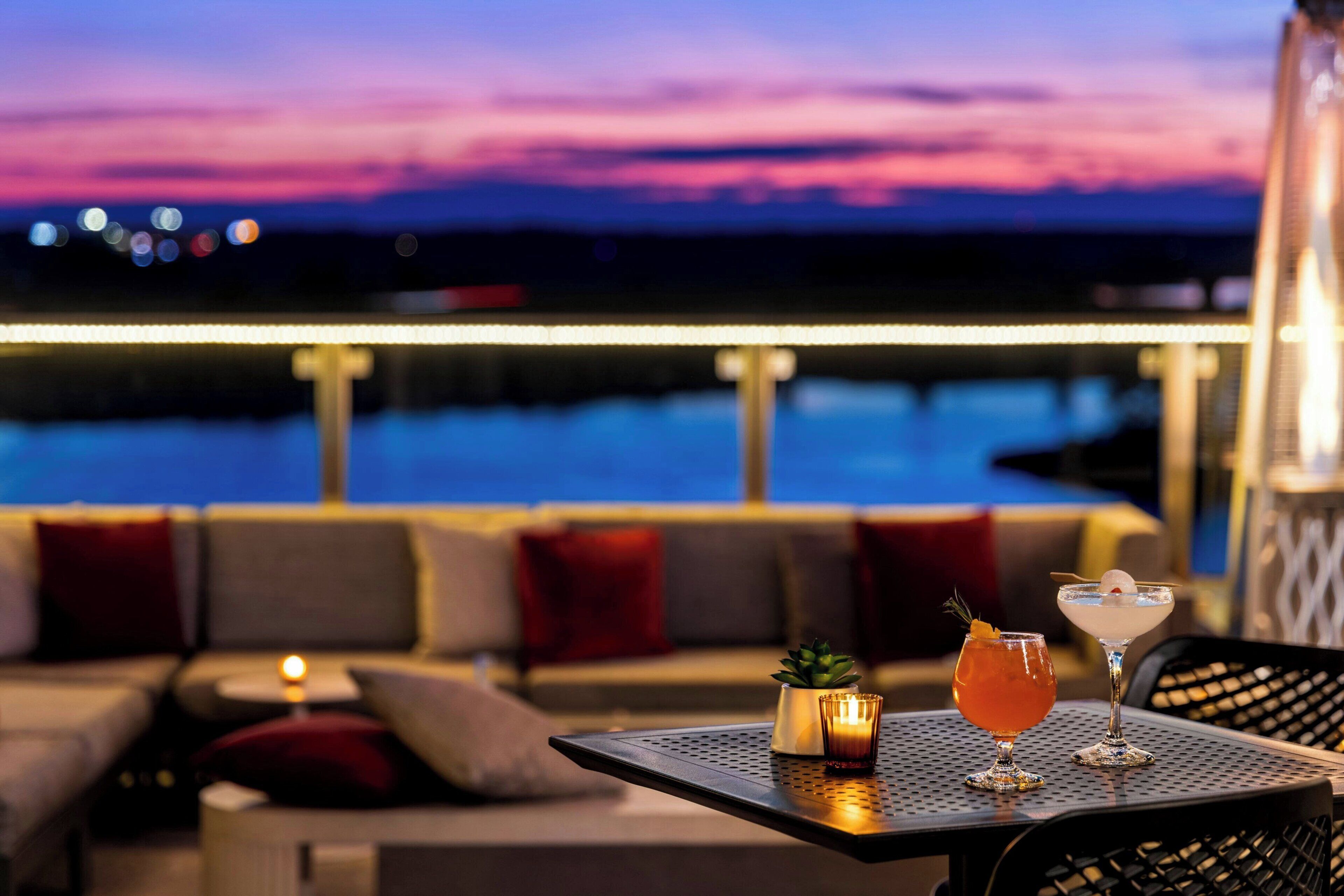 A sunset view from a balcony with two drinks on a table.
