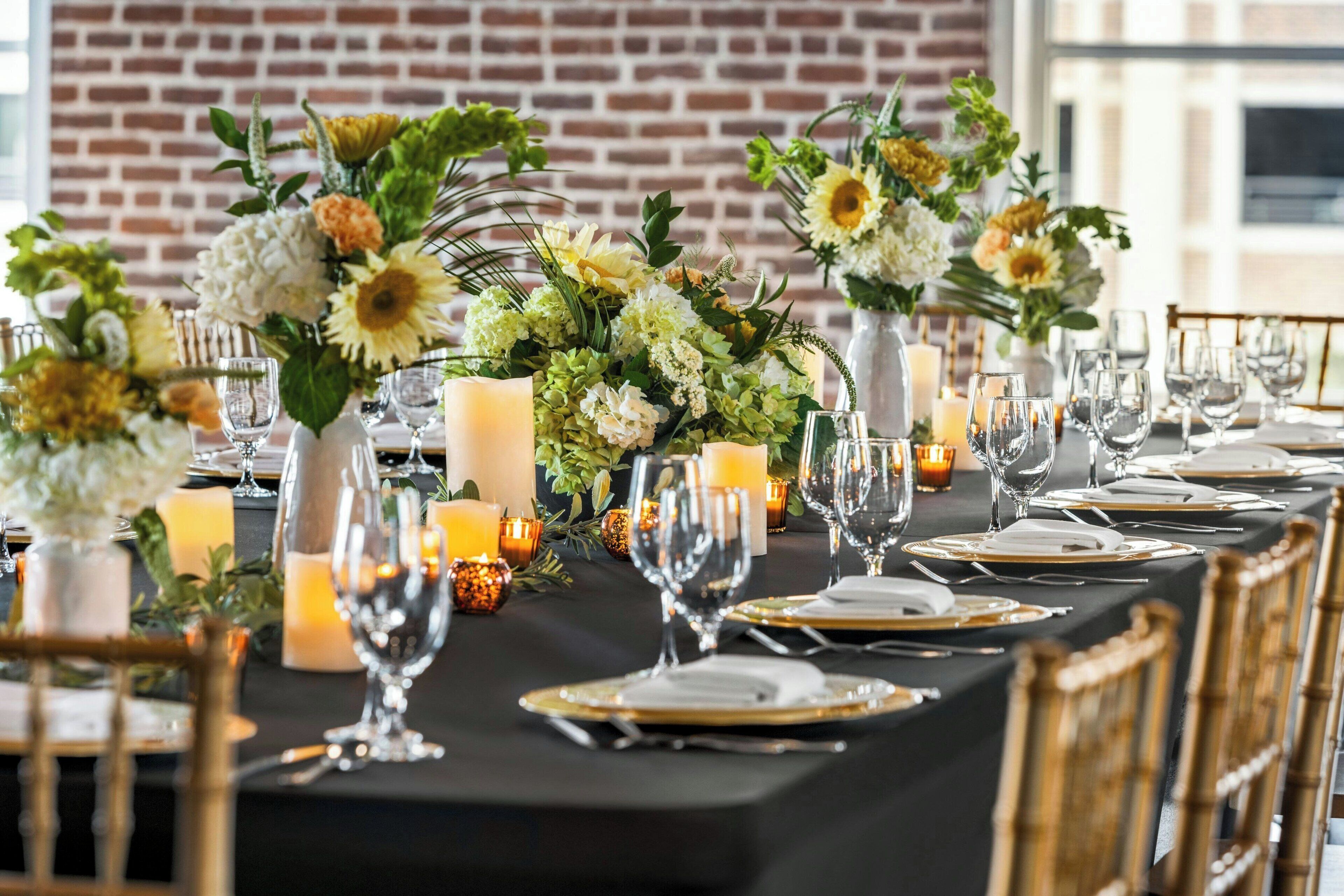 A long dining table set with candles, glassware, and floral centerpieces.