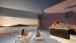 Un espace de détente aménagé sur le toit, avec des chaises longues, un jacuzzi et un pilier en pierre.