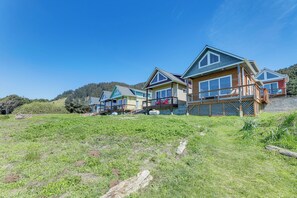 A row of modern cabins with large windows and a wooden exterior, set against a hillside backdrop. - Peaceful Fall Escape: Oregon Home w/ Ocean View (Florence)