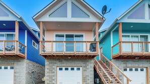 Ein mehrstöckiges Wohngebäude mit einem zentralen Balkon, einer Garage und einer Treppe, die zu den oberen Stockwerken führt.